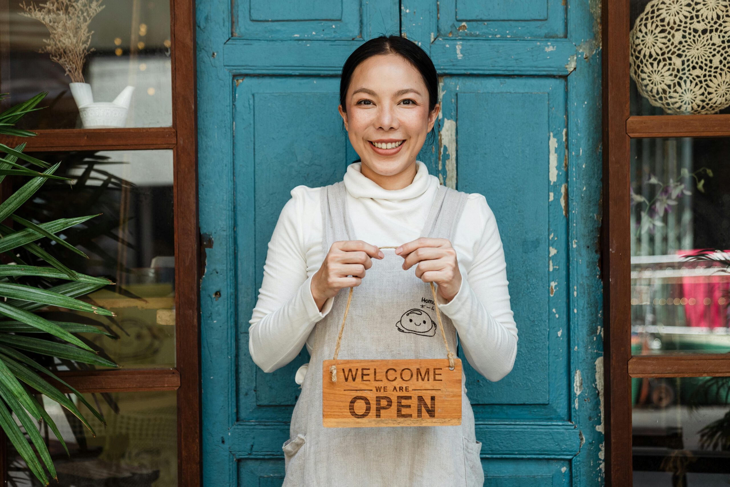 Mujer sosteniendo cartel de abierto de una tienda